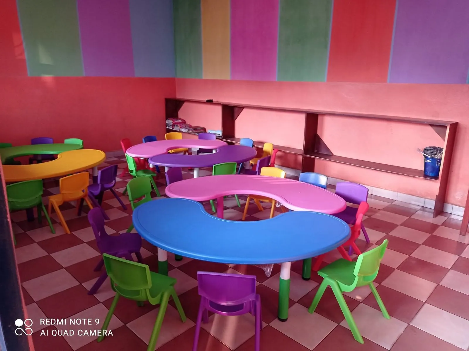 Colourful nursery classroom with bean-shaped tables and bright chairs at BASNPS