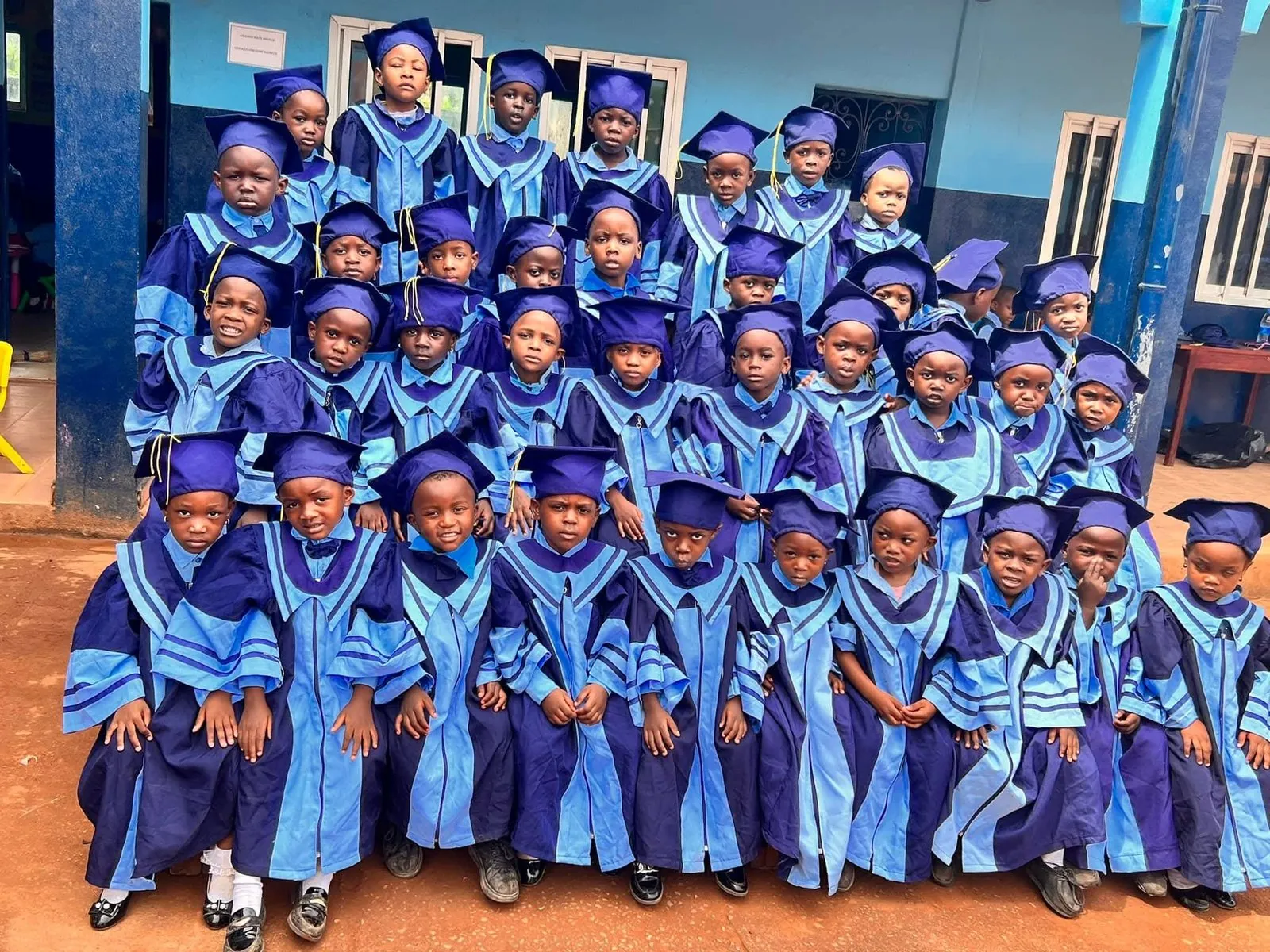 Remise de diplômes — élèves de maternelle BASNPS en toque et toge devant l'école