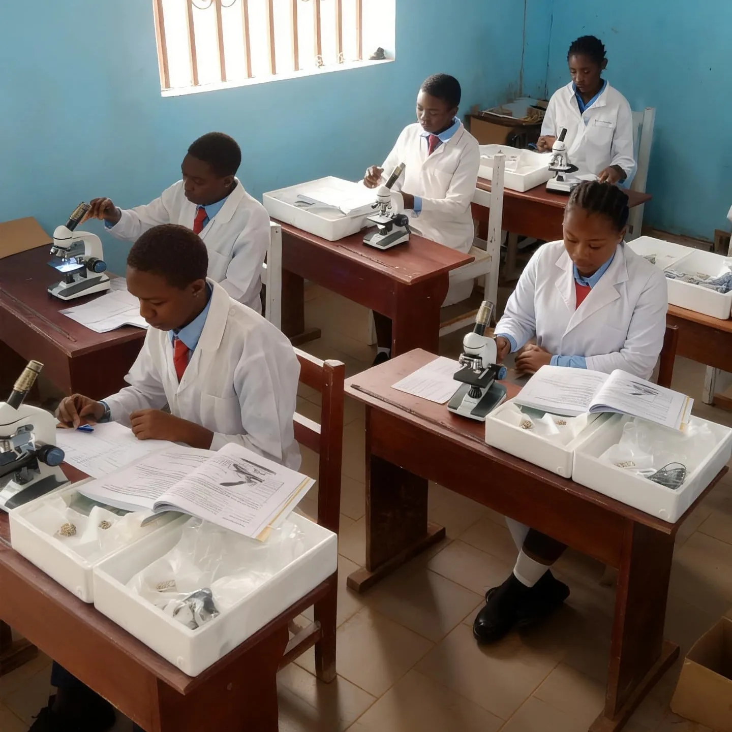 BGS students in white lab coats using microscopes