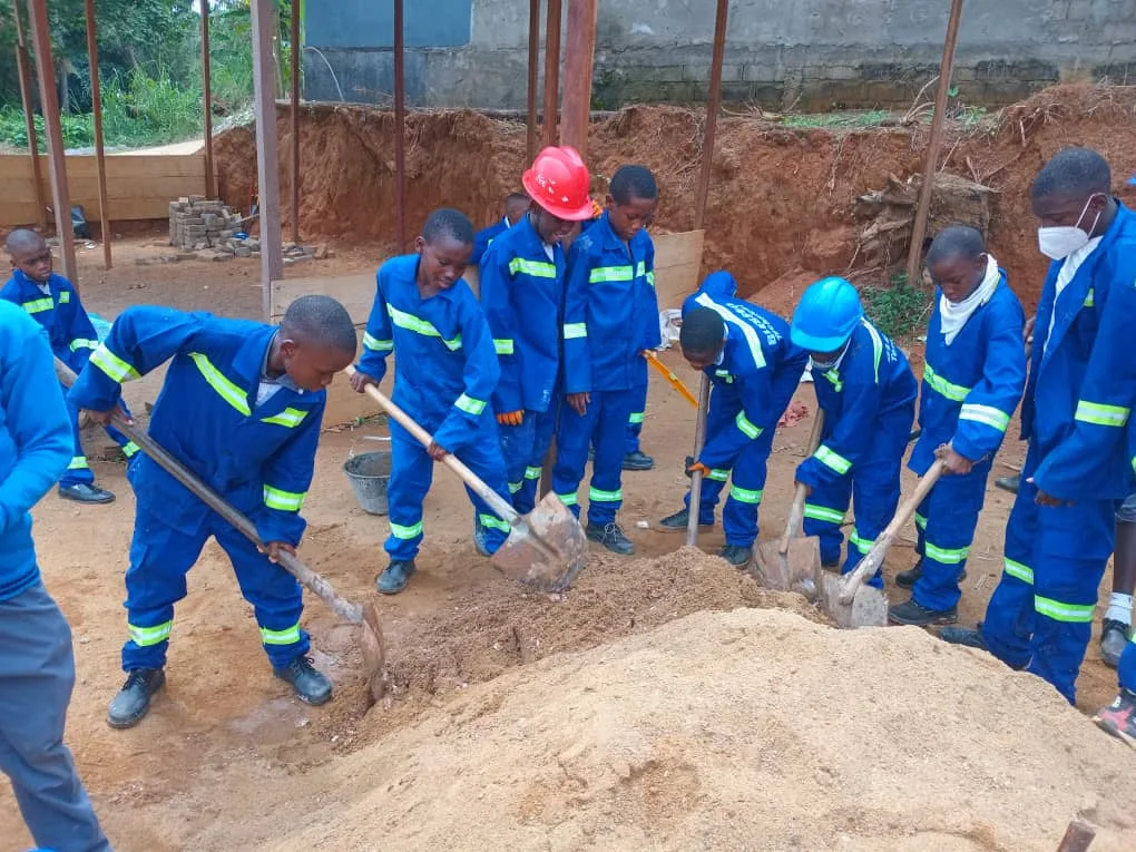 Élèves de BGS pratiquant le malaxage du béton lors du programme de construction